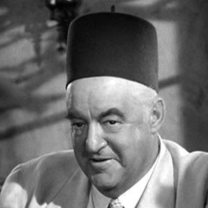 Sydney Greenstreet in character as Signor Ferrari wearing a light colored suit and a fez